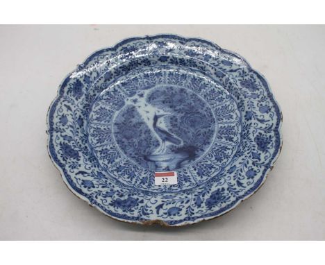 An 18th century Dutch Delft bowl of scalloped circular form, underglaze blue decorated with a bird amidst flowers and foliage
