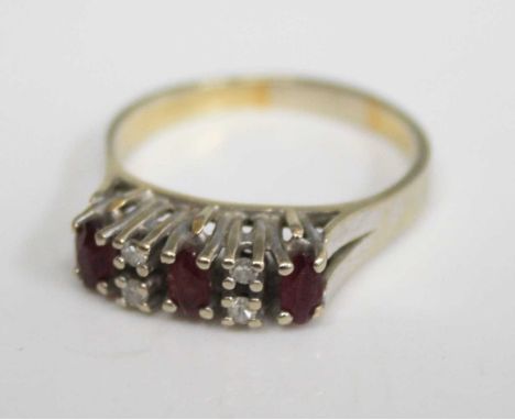 A yellow metal, ruby and diamond dress ring, arranged a three four-claw set oval cut rubies each dispersed with two small rou