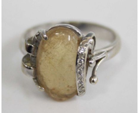 An 18ct white gold rutile quartz dress ring, the cabochon quartz stone held down with a single strap containing five diamond 