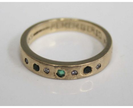 A 9ct gold band ring, set with four diamond highlights, two small sapphires, and a centre emerald, total diamond weight state