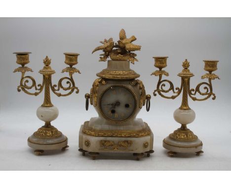 A late 19th century French gilt metal and onyx clock garniture, the central clock surmounted by two gilt metal birds with aco