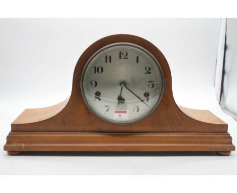 A 1920s walnut cased mantel clock having a silvered dial with Arabic numerals and chiming movement, height 27cmKey present. A