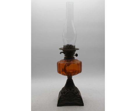 A late Victorian oil lamp having an amber tinted glass font on pierced cast iron base, height 56cm (including chimney)