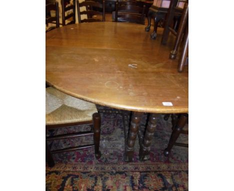 An oak oval gate-legged drop leaf dining table on bobbin turned twin gate leg supports