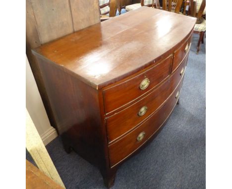 An early 19th century bow-fronted mahogany chest; two half-width over two full-width graduated drawers with stamped brass ova