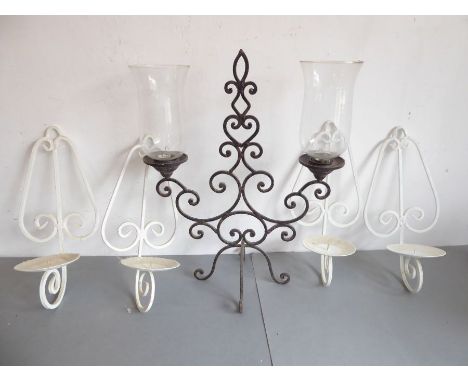 An ornate wrought-iron two-light candelabra with thistle-shaped glass shades, together with a set of four wall-hanging white-