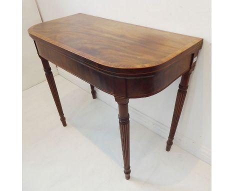 An early 19th century mahogany and rosewood crossbanded foldover top card table; figured frieze and raised on turned tapering