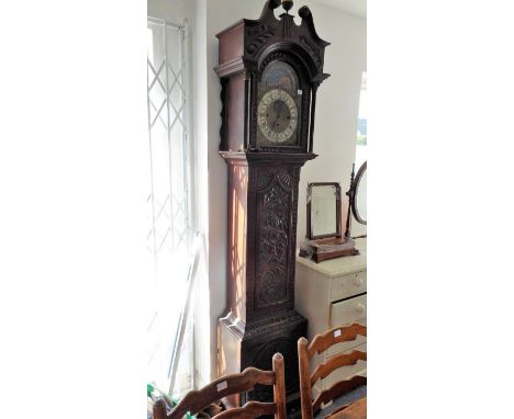 A George III style (later) heavily carved oak eight-day longcase clock; the broken swan-neck pediment surmounted by a brass f