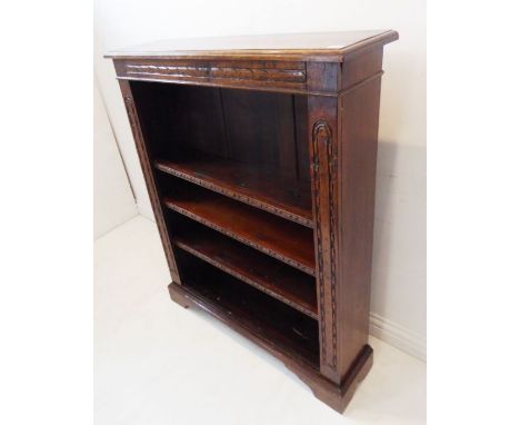 A fine solid oak open bookcase in the 19th century style; carved frieze and uprights and raised on short bracket feet (93cm w