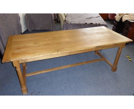 A large and heavy light oak refectory table in excellent condition, the cleated planked top above four gun-barrel style legs 