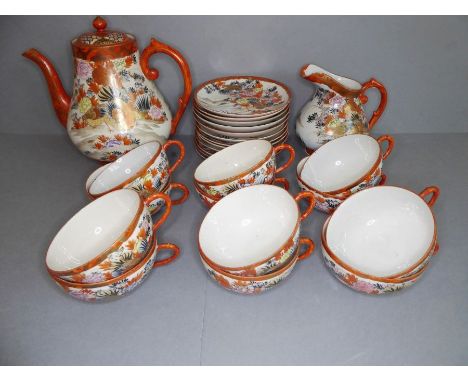 An early 20th century Japanese Kutani tea service: teapot, milk jug and twelve cups and saucers; each piece hand painted and 