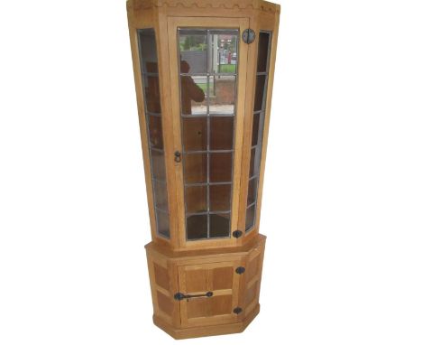 Robert Mouseman Thompson - oak corner cabinet with penny moulded cornice above lead glazed door and panels, projecting base w