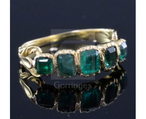 An early Victorian gold and foil backed? emerald five stone half hoop ring, with closed back setting, one green stone probabl