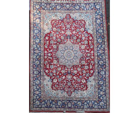 A Kirman red ground carpet, with central foliate medallion in a field of scrolling foliage, with five row border, 12ft 1in by