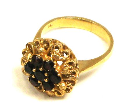A yellow metal cluster ring set with garnets, marked "18K" on the shank, size M 1/2, approx weight 7.3g.