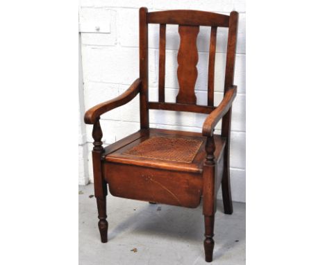 An early 20th century beech commode chair with rattan seat on ring tuned front legs.