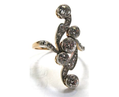 An Art Deco style yellow metal diamond ring set with five spiralling diamonds and diamond chips, total diamond weight approx 