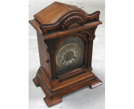 A late 19th century walnut Junghans mantel clock, the shaped pediment with gadrooned decoration to fluted supports and outspl