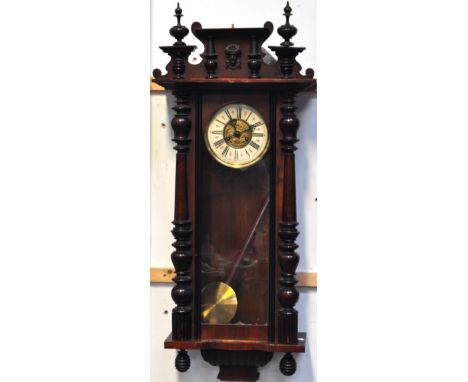 A late 19th early 20th century Vienna style wall clock, the pediment set with carved face in relief flanked by two ring turne