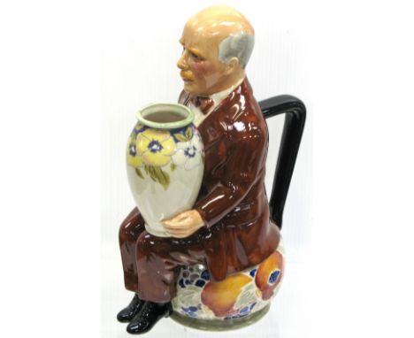 A Moorcroft limited edition figurine of William Moorcroft on a ceramic seat decorated with Pomegranate pattern and holding a 