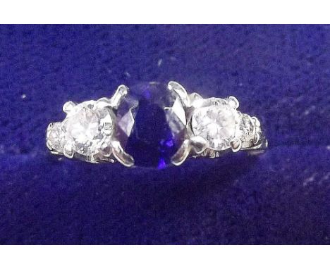 An 18 carat white gold ring set sapphire flanked by four diamonds - size K
