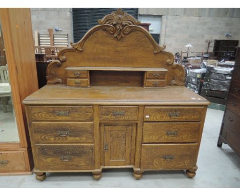 A Victorian scumbled pine dresser base having arch raised back with shelf and drawers over central recess cupboard, flanked b