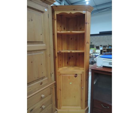 A modern pine corner shelf unit with cupboard under