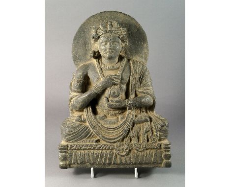 A large Gandharan carved schist figure of Maitraya, the face serene beneath an elaborate coiffure and diadem, circular nimbus