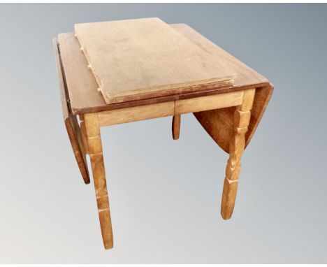 A light oak drop leaf dining table with two leaves 