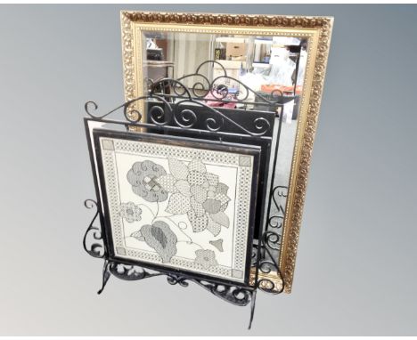 A gilt framed bevelled mirror together with a wrought iron framed needle work fire screen