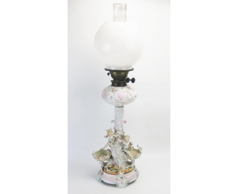 A continental porcelain oil lamp, with squat circular reservoir on a naturalistic stem decorated with figures, on a circular 