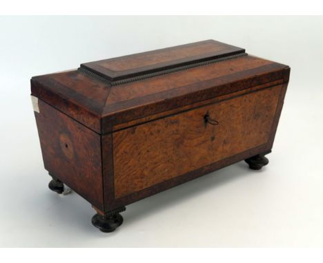 A 19th century figured walnut and tea caddy of sarcophagus outline, with shallow domed hinged lid enclosing a central well an
