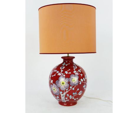 A large Italian pottery lamp, of ovoid form with floral decoration to a wine red field, with shade. overall height including 