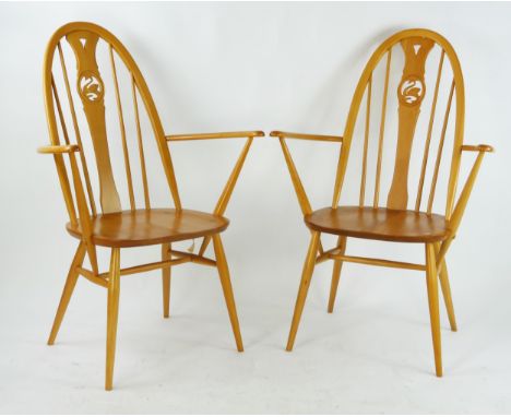 A pair of Ercol elbow chairs, the arched stickbacks with central carved swan splat above a solid seat on turned legs. (2). 