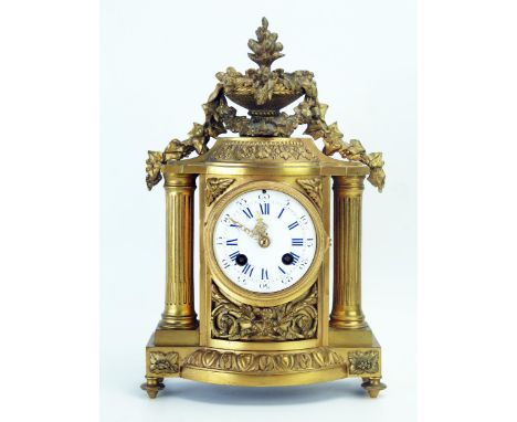 A late 19th century gilt metal mantel clock, of arched outline surmounted with a vase of flowers and garland, with 9cm enamel