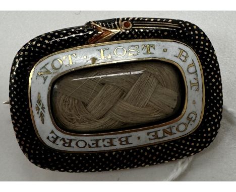 An early 19th Century yellow metal and enamel decorated mourning brooch set with plaited lock of hair, inscribed "Not lost bu