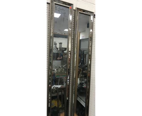 A pair of modern slim silvered framed wall mirrors with bevel edged outer plates and beaded decoration enclosing the central 