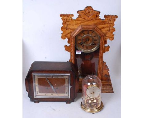 A late 19th century American oak cased gingerbread type clock having a circular gilt dial with Roman numerals and eight day m