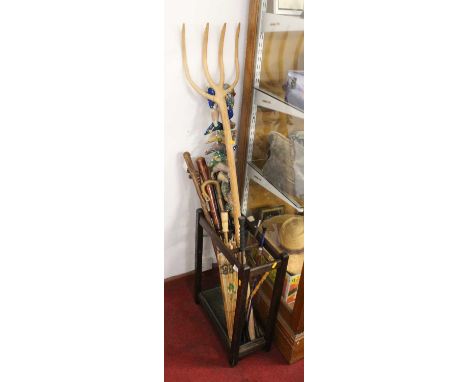 A collection of various walking sticks, riding crops and parasols and a stick stand