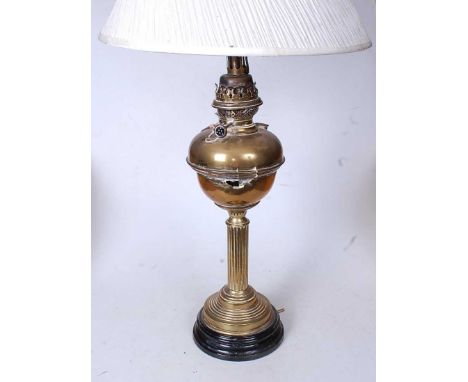 An early 20th century brass pedestal oil lamp, later converted for electricity, having a pleated silk shade, h.80cm 