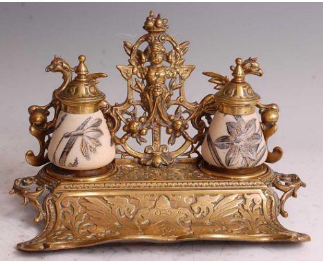 A late Victorian heavy gilt brass desk stand, having scoop pen tray and twin inkwells, the brass elaborately cast with griffi
