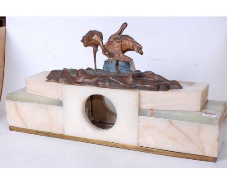 An Art Deco onyx and polished hardstone mantel clock case, mounted with a spelter model of birds, w.58cm