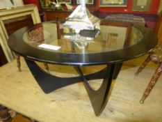 A mid C20th low table of circular form with inset glass top