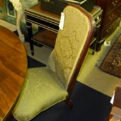 A Victorian rosewood nursing chair in floral detail on turned feet