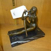 A bronze cast of a seated semi-nude female on a marble base