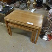 A nest of three teak low table on square section supports