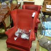 A pair of wingback armchairs upholstered in red fabric