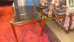 A pair of modern smoky glass top low tables raised on brass cylindrical support