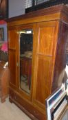 An Edwardian inlaid mahogany wardrobe with bevelled mirrored door above base drawer