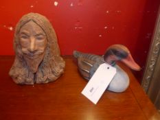 A terracotta bust of a man and a painted wooden model of a duck